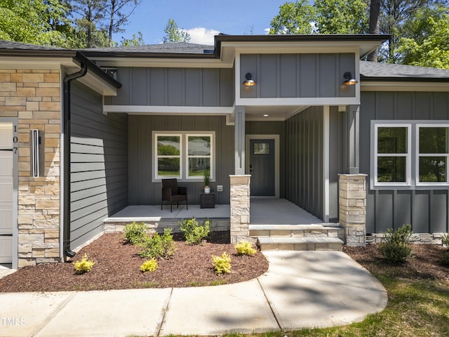 view of exterior entry featuring a shingled roof, covered porch, and board and batten siding