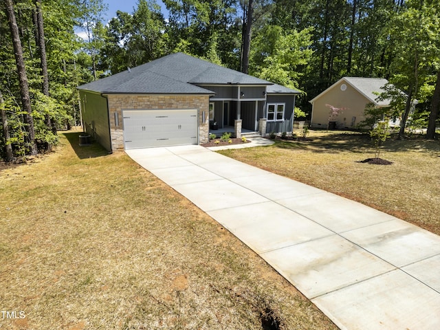 view of front of property with driveway, a front lawn, an attached garage, a shingled roof, and stone siding
