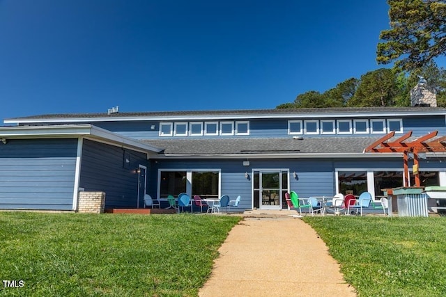 rear view of property with a lawn, a pergola, and a shingled roof