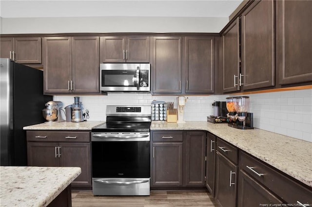 504 Loom Dr, Fayetteville, NC 28306 - kitchen with appliances with stainless steel finishes, dark brown cabinets, backsplash, light stone counters, and light wood-style flooring