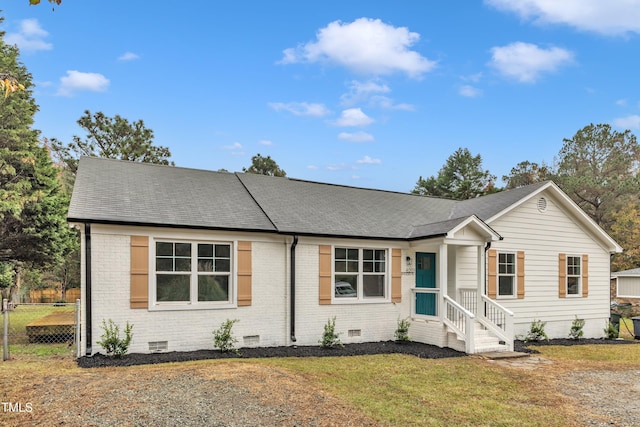 ranch-style house featuring brick siding, a shingled roof, a front yard, and crawl space