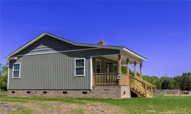 view of property exterior featuring stairway, crawl space, a chimney, and covered porch