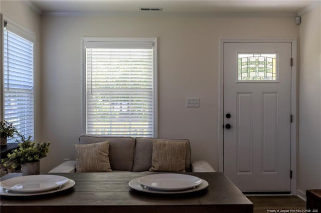 living area featuring dark wood-type flooring, visible vents, crown molding, and a healthy amount of sunlight