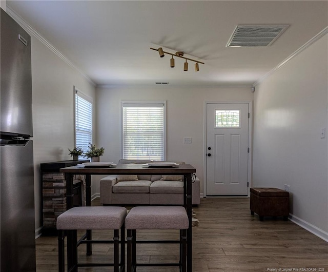 entryway with wood finished floors, visible vents, and ornamental molding