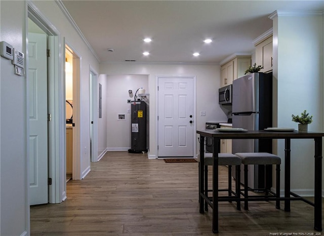 kitchen featuring stainless steel appliances, water heater, ornamental molding, and dark wood-style flooring