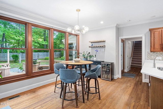 108 Nimbus Ct, Cary, NC 27513 - dining room featuring wine cooler, baseboards, stairway, light wood-type flooring, and crown molding