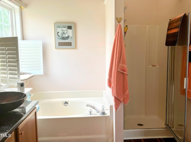 bathroom featuring a stall shower, a garden tub, and vanity