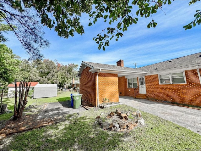 332 Rainier Dr, Fayetteville, NC 28314 - view of side of home featuring brick siding, a yard, entry steps, and a chimney