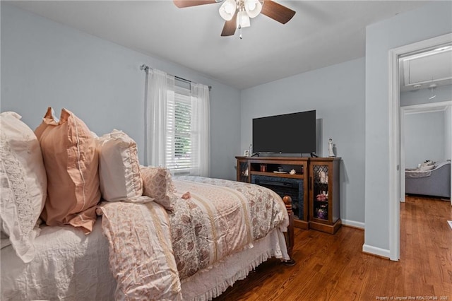 bedroom featuring attic access, baseboards, a ceiling fan, and wood finished floors