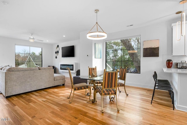 211 W Coporation, Durham, NC 27701 - dining space featuring light wood-style floors, a ceiling fan, a glass covered fireplace, recessed lighting, and baseboards