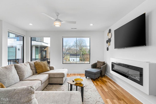 211 W Coporation, Durham, NC 27701 - living room with healthy amount of natural light, light wood finished floors, a glass covered fireplace, a ceiling fan, and recessed lighting