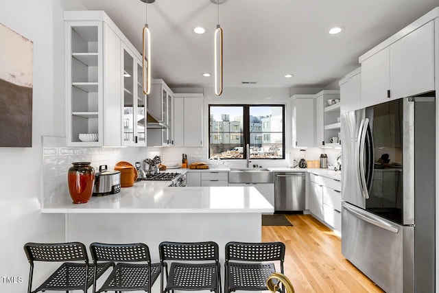 211 W Coporation, Durham, NC 27701 - kitchen featuring stainless steel appliances, a peninsula, a sink, light countertops, and decorative backsplash