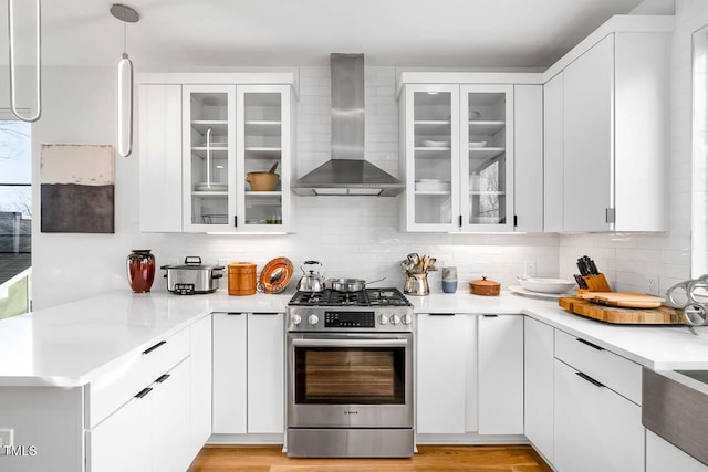 211 W Coporation, Durham, NC 27701 - kitchen with stainless steel range with gas stovetop, wall chimney range hood, white cabinetry, and light countertops