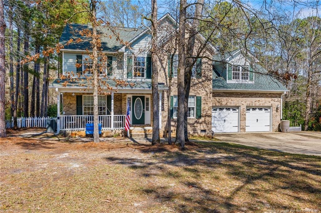 51 Sandy Pt, Sanford, NC 27332 - view of front facade with driveway, covered porch, fence, a garage, and brick siding