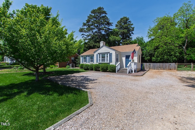view of front of property with fence, driveway, a chimney, and a front lawn