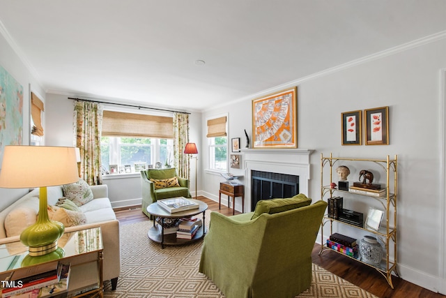 living area with baseboards, ornamental molding, a fireplace, and wood finished floors