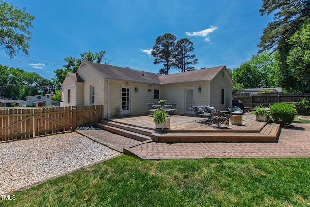 rear view of property with a fenced backyard, a wooden deck, and a gate