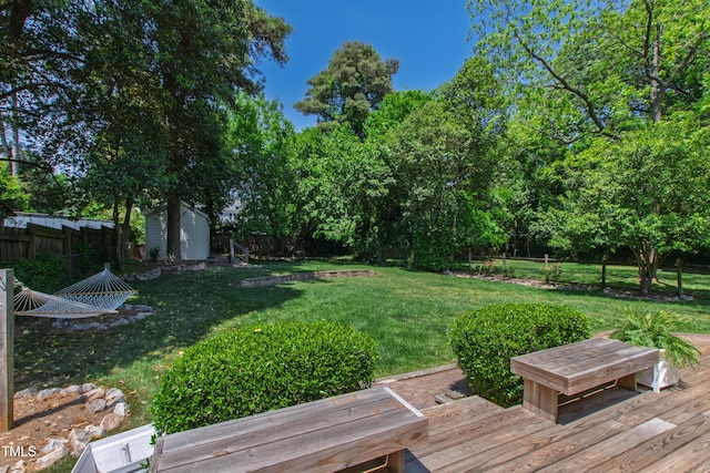 view of yard with a wooden deck, an outbuilding, a fenced backyard, and a storage unit
