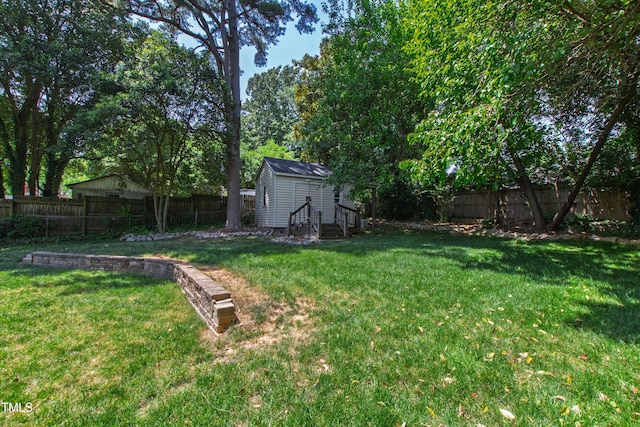 view of yard with a fenced backyard, an outdoor structure, and entry steps