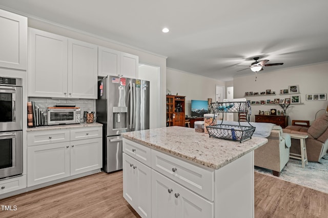 kitchen featuring light wood-type flooring, stainless steel appliances, ceiling fan, and open floor plan