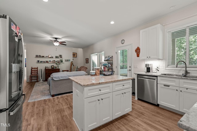 kitchen featuring open floor plan, a healthy amount of sunlight, stainless steel appliances, and a sink