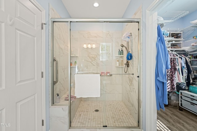 full bathroom with a stall shower, recessed lighting, a walk in closet, and wood finished floors