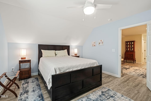 bedroom with baseboards, light wood-type flooring, a ceiling fan, and lofted ceiling