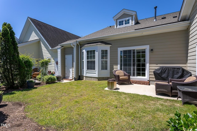 rear view of house with a patio area, a yard, and a shingled roof