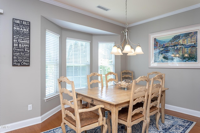 dining space with a chandelier, baseboards, wood finished floors, and crown molding