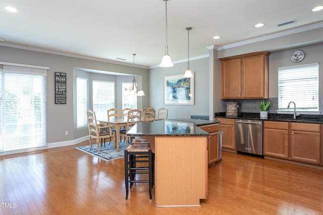 kitchen featuring dishwasher, a sink, a breakfast bar, a center island, and light wood-type flooring