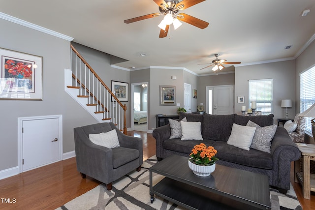 living area with wood finished floors, a ceiling fan, stairs, ornamental molding, and baseboards