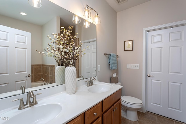 bathroom featuring tile patterned flooring, double vanity, toilet, and a bathtub