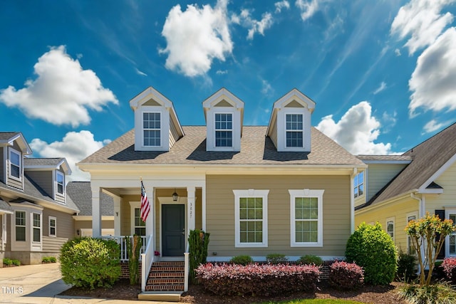 new england style home with covered porch and a shingled roof