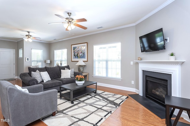 3827 Heritage Spring Cir, Wake Forest, NC 27587 - living room featuring light wood-type flooring, a ceiling fan, a glass covered fireplace, baseboards, and crown molding