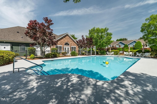 community pool featuring fence and a patio area