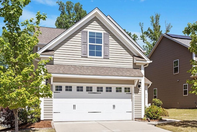 view of front of house with an attached garage, driveway, and roof with shingles