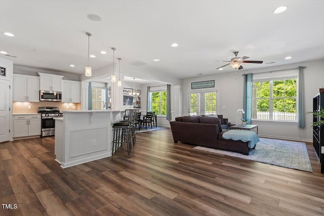living area with baseboards, a ceiling fan, recessed lighting, and dark wood-type flooring