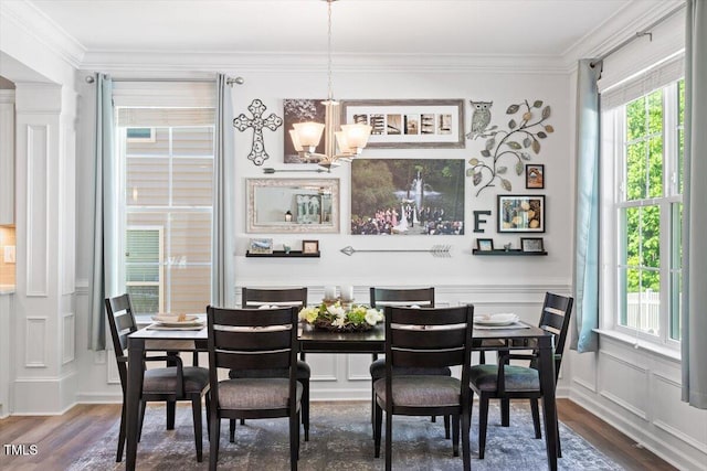 dining area featuring a decorative wall, ornamental molding, a notable chandelier, and dark wood-type flooring