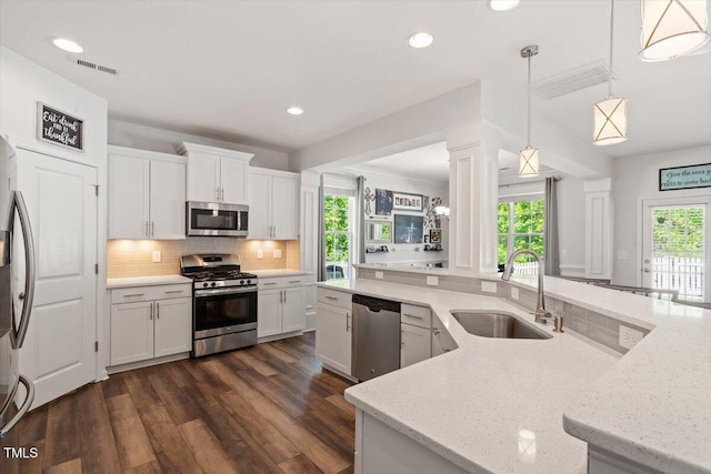 kitchen featuring appliances with stainless steel finishes, a sink, decorative backsplash, visible vents, and dark wood-style floors