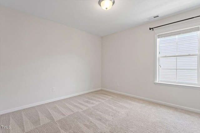 empty room featuring baseboards, light carpet, and visible vents