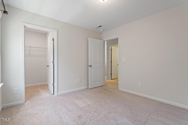 unfurnished bedroom with baseboards, carpet flooring, a walk in closet, and a closet
