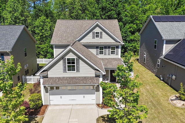 view of front facade featuring roof with shingles, fence, an attached garage, a front lawn, and concrete driveway