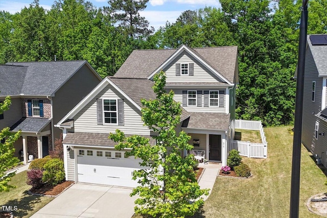 craftsman-style house featuring roof with shingles, a front yard, fence, concrete driveway, and an attached garage
