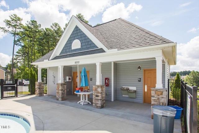 back of house featuring a gate, fence, covered porch, and a shingled roof