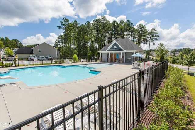pool with fence, an outbuilding, and a patio area