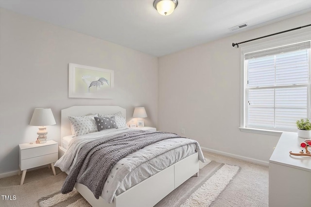 bedroom with baseboards, visible vents, and light carpet