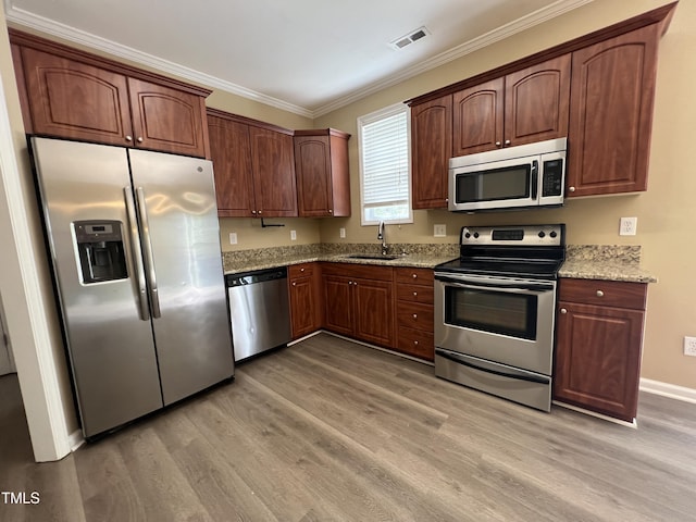 kitchen featuring crown molding, a sink, light wood finished floors, appliances with stainless steel finishes, and visible vents
