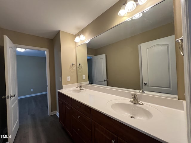 bathroom with double vanity, wood finished floors, baseboards, and a sink