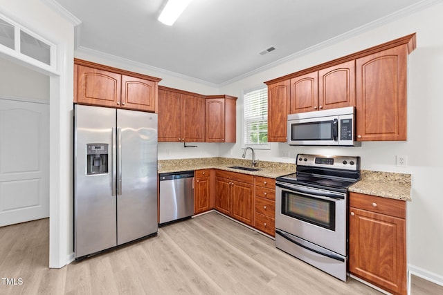 125 Occidental Dr, Holly Springs, NC 27540 - kitchen with stainless steel appliances, light wood-style flooring, a sink, light stone countertops, and ornamental molding