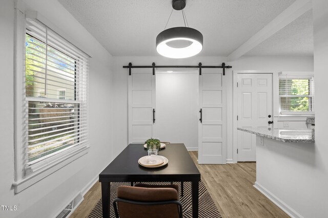 1613 Kilmer Ter, Durham, NC 27703 - interior space with baseboards, a textured ceiling, a barn door, and light wood-style flooring
